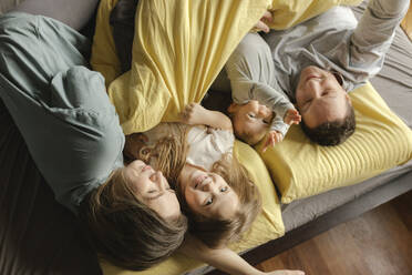 Happy family lying down on bed at home - VIVF00787