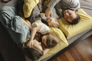 Familie liegt zusammen auf einem Bett zu Hause - VIVF00788
