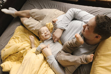 Father playing with son on bed at home - VIVF00789