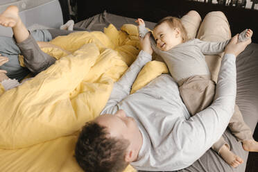 Father having fun with son on bed at home - VIVF00790