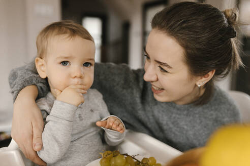 Mother looking at son eating grapes at home - VIVF00799