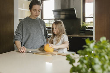 Tochter lernt zu Hause von ihrer Mutter, gelbe Paprika zu schneiden - VIVF00802