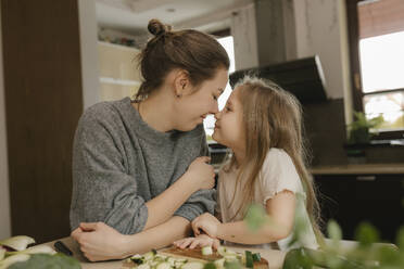 Mother and daughter rubbing noses in kitchen - VIVF00810