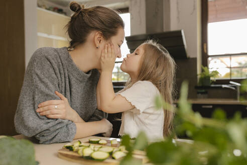 Daughter kissing mother in kitchen - VIVF00812
