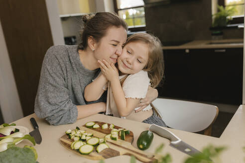 Mutter umarmt und küsst Tochter in der Küche - VIVF00813