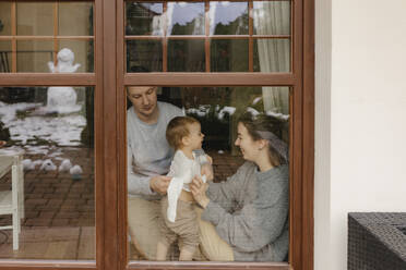 Spielende Familie im Haus durch Glasfenster gesehen - VIVF00818