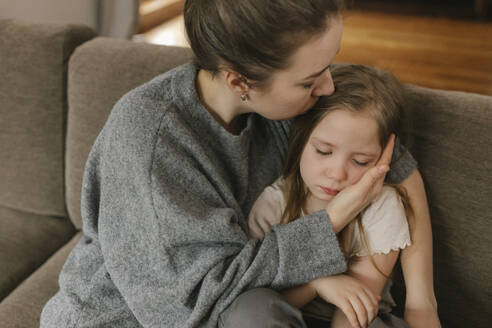 Mother kissing sad daughter at home - VIVF00825