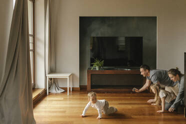 Playful family crawling on hardwood floor at home - VIVF00836