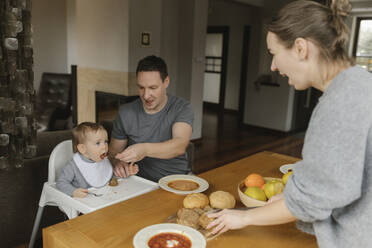 Father feeding baby boy at dining table at home - VIVF00841
