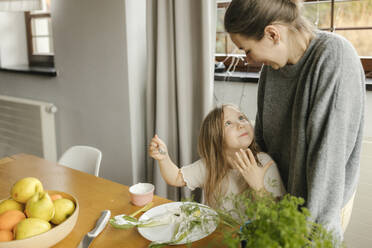 Happy girl talking with mother at dining table - VIVF00845