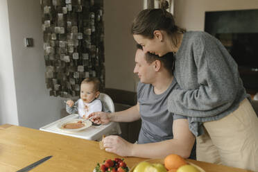 Father and mother feeding son at dining table - VIVF00847