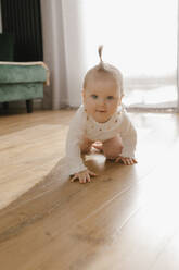 Niedliches kleines Mädchen krabbelt auf dem Parkettboden zu Hause - VIVF00875