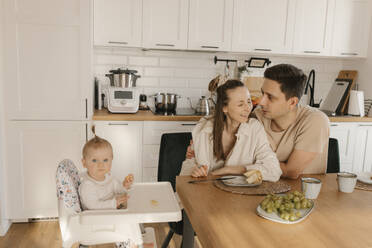 Happy mother and father sitting with cute daughter at dinner table - VIVF00885