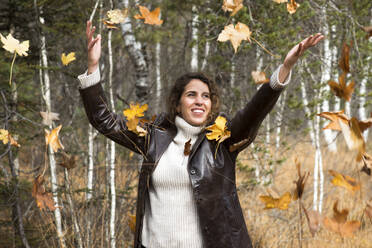 Happy woman playing with autumn leaves at forest - HHF05892