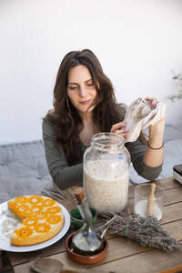 Frau nimmt fermentierten Bulgur zur Herstellung von veganem Käse - PCLF00458