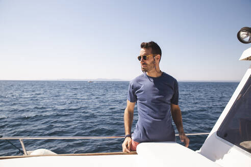 Man wearing sunglasses standing on yacht at sunny day - PCLF00473