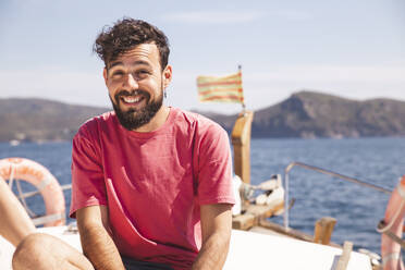 Lächelnder Mann, der seinen Urlaub auf einer Yacht an einem sonnigen Tag genießt - PCLF00477