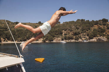 Carefree man jumping from yacht in sea - PCLF00487
