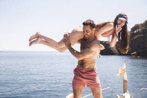 Man carrying girlfriend on yacht at sunny day - PCLF00495