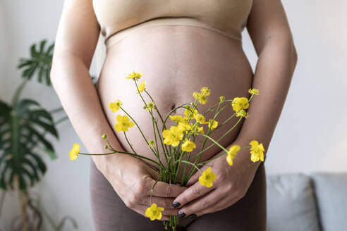 Schwangere Frau hält einen Blumenstrauß zu Hause - AAZF00431