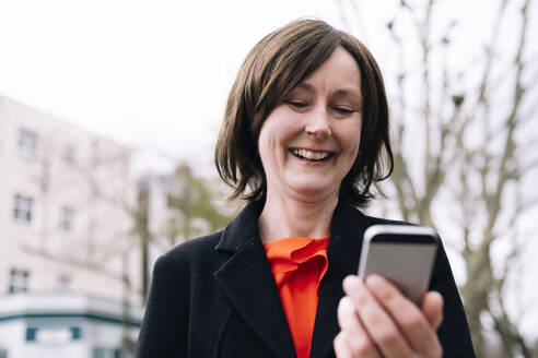 Lächelnde Frau mit Blazer und Smartphone - AMWF01316