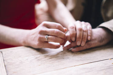 Woman holding hand of man and consoling at table - AMWF01318