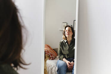 Reflection of woman in mirror by wall at home - ASGF03569