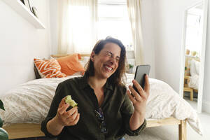 Glückliche Frau bei einem Videoanruf über ein Smartphone zu Hause - ASGF03583