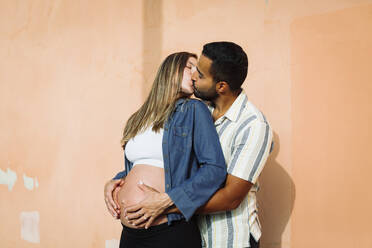 Schwangere Frau küsst Mann an der Wand - DCRF01587