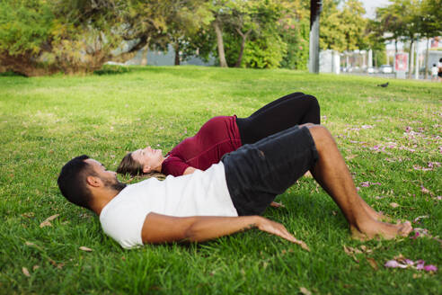 Mann beim Sport mit schwangerer Frau im Gras liegend - DCRF01597