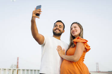 Smiling man taking selfie with pregnant woman - DCRF01628