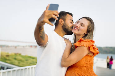 Man kissing and taking selfie with pregnant woman - DCRF01629