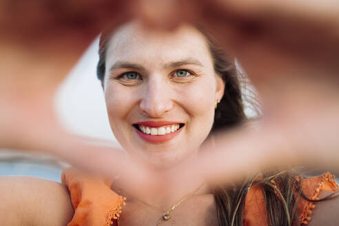 Lächelnde Frau, die mit den Händen ein Herz formt - DCRF01637