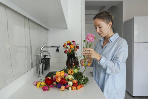 Frau schneidet Blumen in der Küche zu Hause - SYEF00387