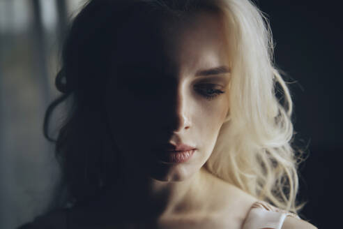 Depressed blond woman in darkroom - AZF00519