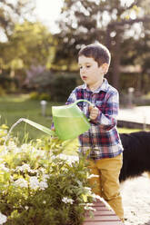 Junge bewässert Pflanzen im Hinterhof - ONAF00517