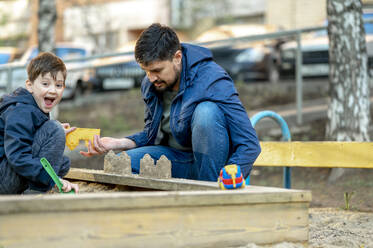 Vater und Sohn bauen Sandburgen im Park - ANAF01379