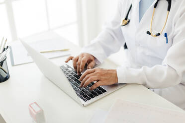 Ärztin, die mit einer EHR-Software auf einem Laptop arbeitet und auf der Tastatur tippt, um nach Patientendaten im System zu suchen. Weibliche Fachkraft im Gesundheitswesen, die Technologie zur Verwaltung medizinischer Informationen in ihrer Privatpraxis nutzt. - JLPSF29568