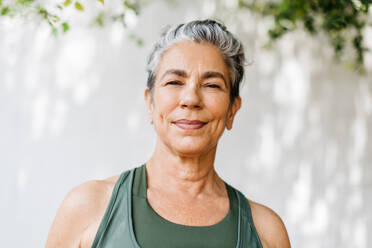Porträt einer reifen Frau mit grauen Haaren, die in Fitnesskleidung im Freien steht. Aktive ältere Frau, die ihr morgendliches Trainingsprogramm absolviert und durch regelmäßige Bewegung einen gesunden Lebensstil im Ruhestand beibehält. - JLPSF29582