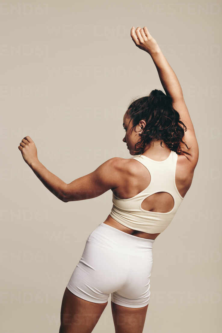 Sports woman improving her lean physique with muscle-toning body movements  in a studio. Female athlete working out in sportswear, engaging in balance  and flexibility enhancing techniques. stock photo