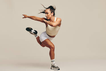 Fit woman having a strength training session in studio. Sporty young woman performing intense workout moves, demonstrating her dedication to a healthy and athletic lifestyle. - JLPSF29638