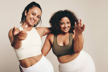 Zwei junge Frauen in Sportkleidung tanzen und trainieren zusammen und verkörpern einen gesunden und aktiven Lebensstil. Energetische Sportlerinnen, die ihre gemeinsame Leidenschaft für Fitness in einem Studio zum Ausdruck bringen. - JLPSF29665