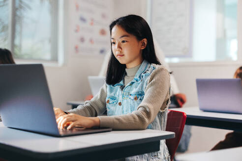 Young girl works on a computer programming exercise in a classroom, exploring the digital world with her newly acquired coding skills. Female child sitting in a computer science lesson, getting STEM education in a kids coding academy. - JLPSF29707