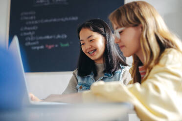 Female students working collaboratively in a coding class to learn programming concepts and computer science. Two children assisting and engaging with each other to build a foundation for technology education. - JLPSF29725