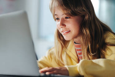 Junge Schülerin, die in einer Klasse mit einem Laptop programmieren lernt. Sie schaut auf ihren Bildschirm und erkundet die digitale Welt mit ihren neu erworbenen Programmier- und Computerkenntnissen. - JLPSF29746
