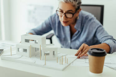Architektin bei der Arbeit an einer 3D-Darstellung eines Hauses, die den Entwurf in ihrem Büro visualisiert und analysiert. Leitende Designerin, die ihre Erfahrung in der Hausarchitektur bei einem Hausbau einsetzt. - JLPSF29814