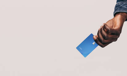 Ein männlicher Einkäufer hält eine Kreditkarte in der Hand und repräsentiert damit den wachsenden Lebensstil bargeldloser Transaktionen und mobiler Zahlungen. Mit der Einführung von Tap-to-Pay sind Bankgeschäfte mit der Kreditkarte einfach geworden. - JLPPF01638