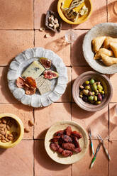 Draufsicht auf spanische Mezze mit verschiedenen Käsesorten und Nüssen neben Oliven und Chorizzo auf dem Tisch - ADSF43870