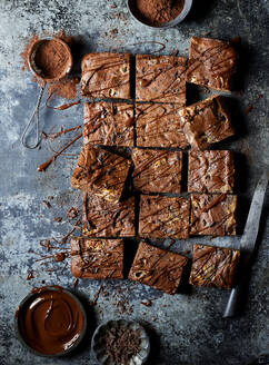 Draufsicht auf leckere Schokoladen-Brownies mit Topping und Kakaopulver auf grauer Fläche - ADSF43890