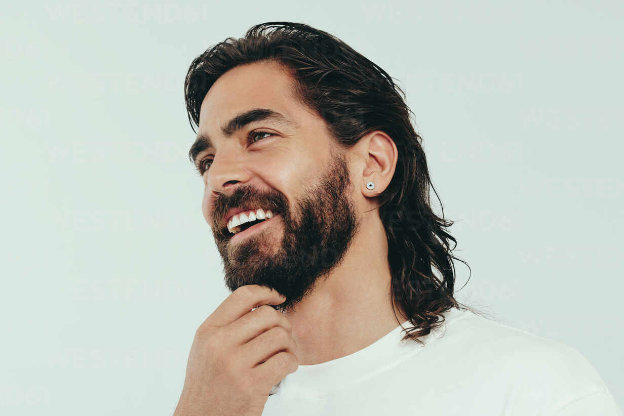 https://us.images.westend61.de/0001820595pw/man-with-a-beard-and-a-radiant-skin-tone-stands-in-a-studio-wearing-a-perfect-smile-on-his-face-happy-young-man-embracing-his-beauty-and-masculine-looks-expressing-confidence-and-self-assurance-JLPSF30032.jpg